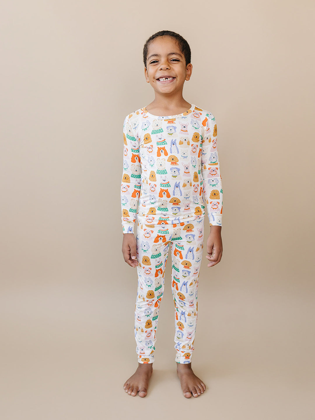Smiling child standing with arms at their sides in the Puppy Club dog-print bamboo two-piece set.
