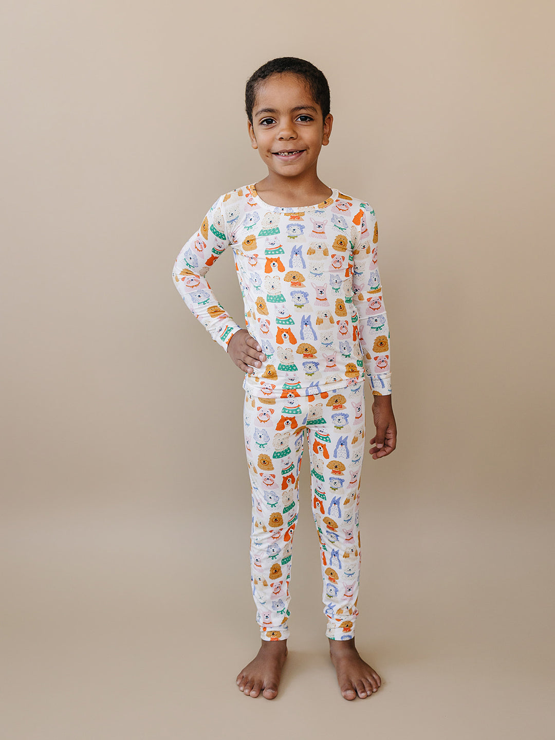 Child standing with one hand on their hip in the Puppy Club dog-print bamboo top and matching pants.