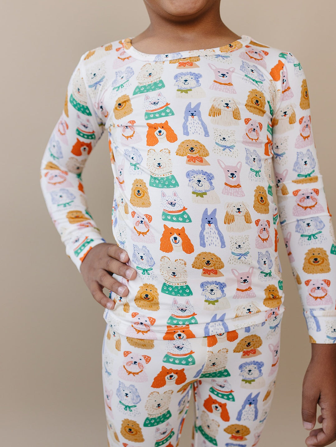 Close-up of a child wearing the Puppy Club bamboo two-piece set with colorful dog illustrations on white.