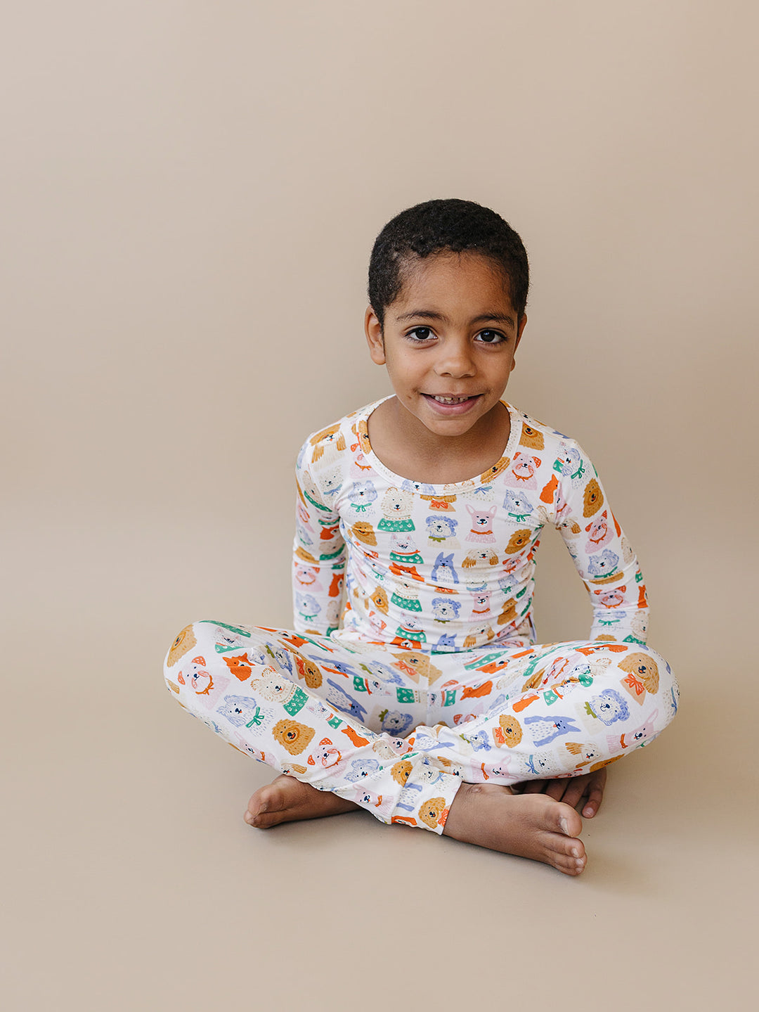 Child sitting cross-legged in the Puppy Club bamboo two-piece set.