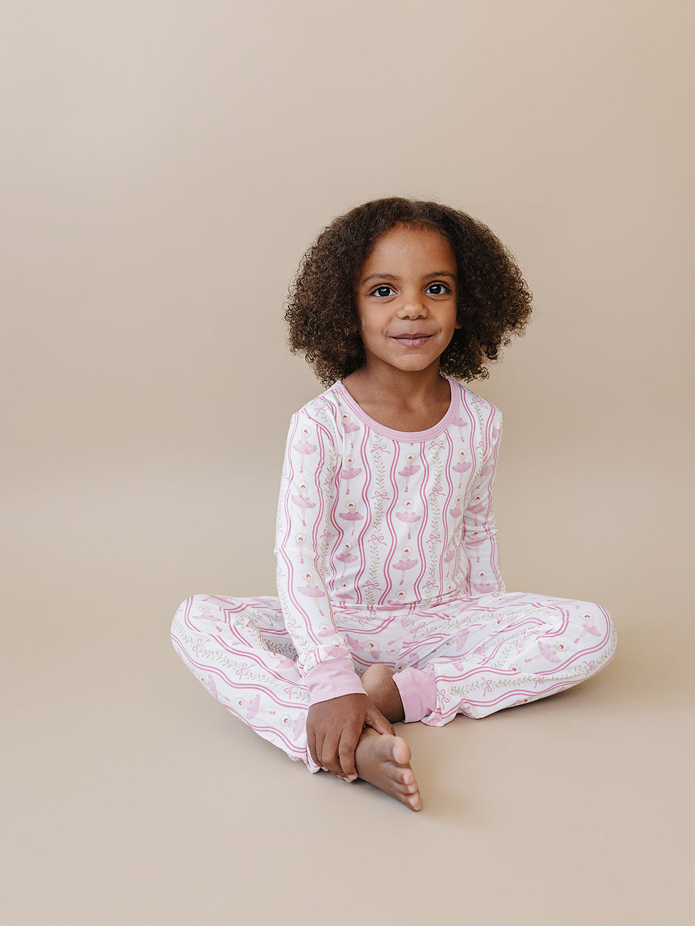 Child sitting cross-legged in the Little Ballerina bamboo top and matching pants.