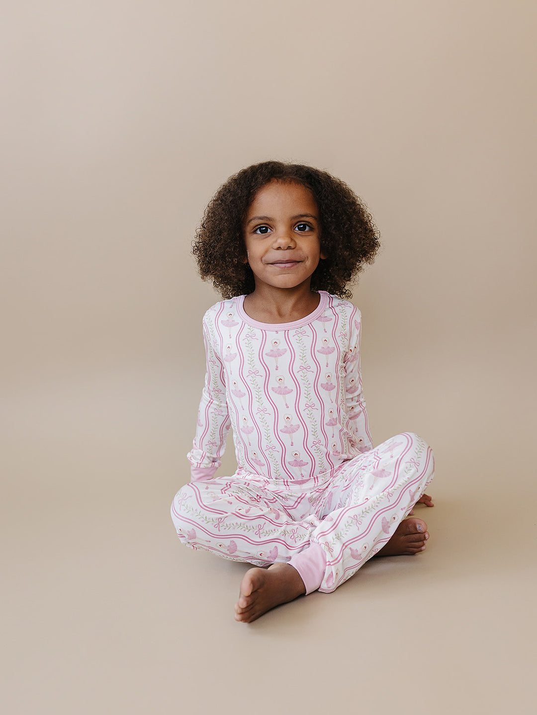 Child sitting and modeling the Little Ballerina bamboo two-piece pajama set.