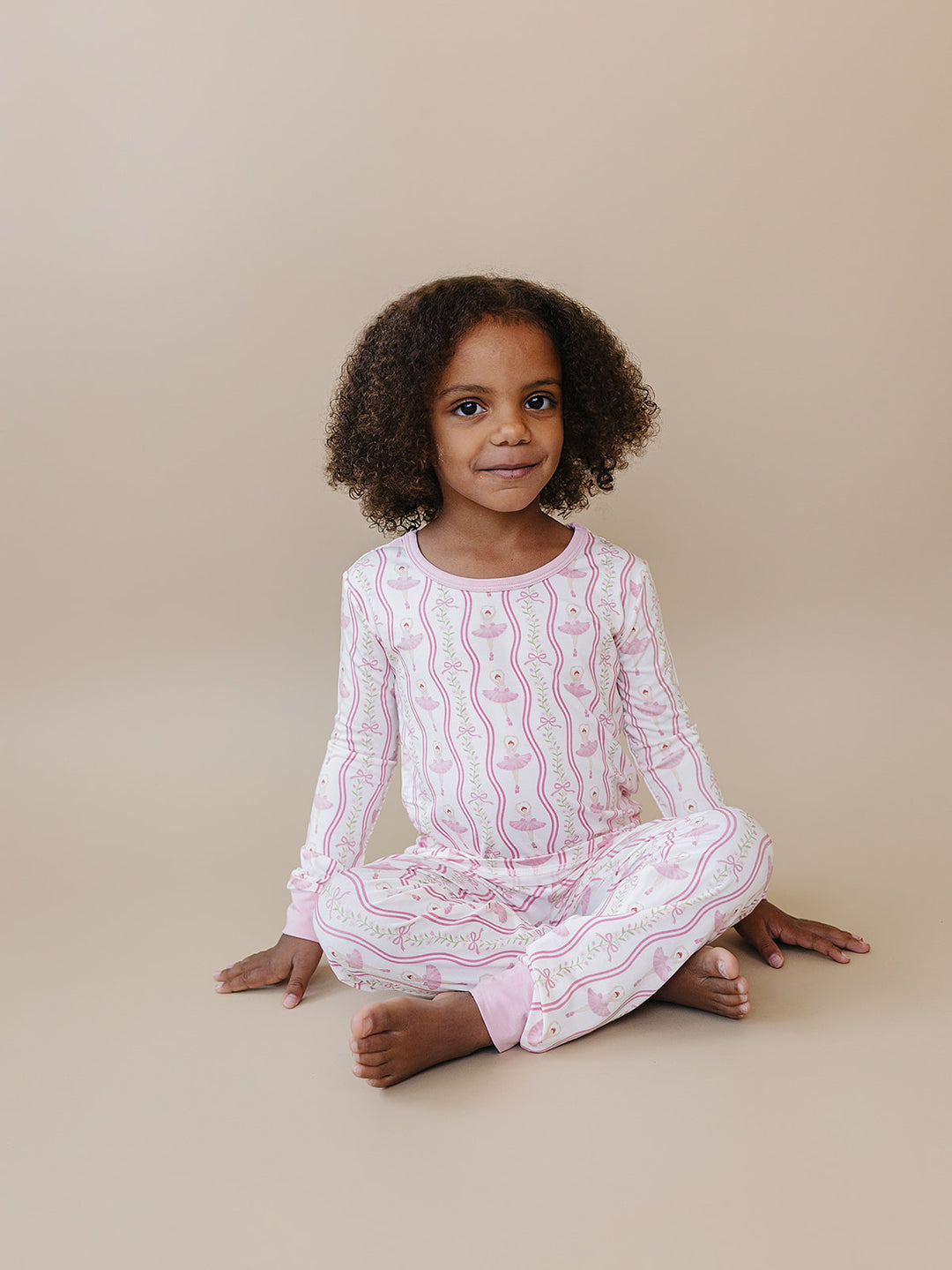 Child sitting cross-legged in the Little Ballerina bamboo two-piece outfit.