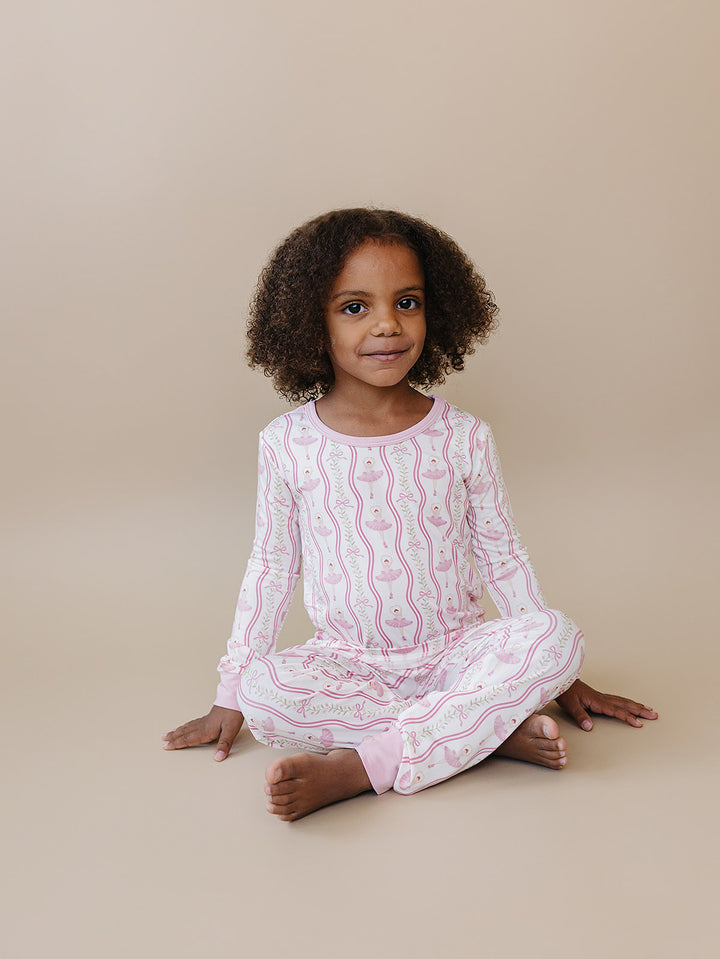 Child sitting cross-legged in the Little Ballerina bamboo two-piece outfit.