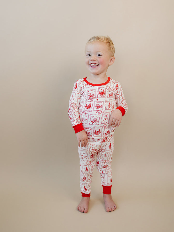 Child looking to the side while wearing North Pole Stamps Christmas pajamas with red cuffs.