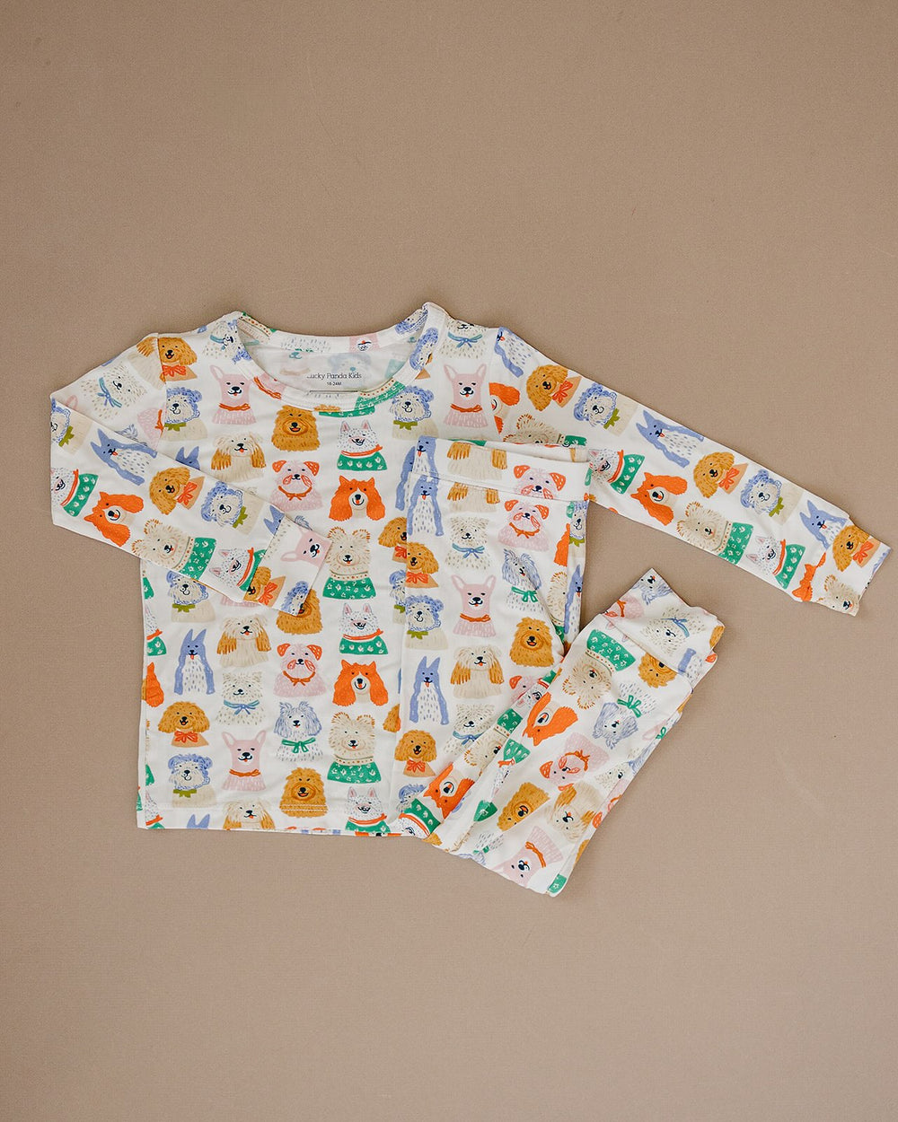 Close-up of a child wearing the Puppy Club bamboo two-piece set with colorful dog illustrations on white.