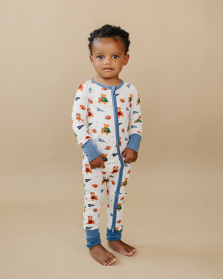 Full-length view of a child modeling the Touchdown Teddy bamboo zip romper.
