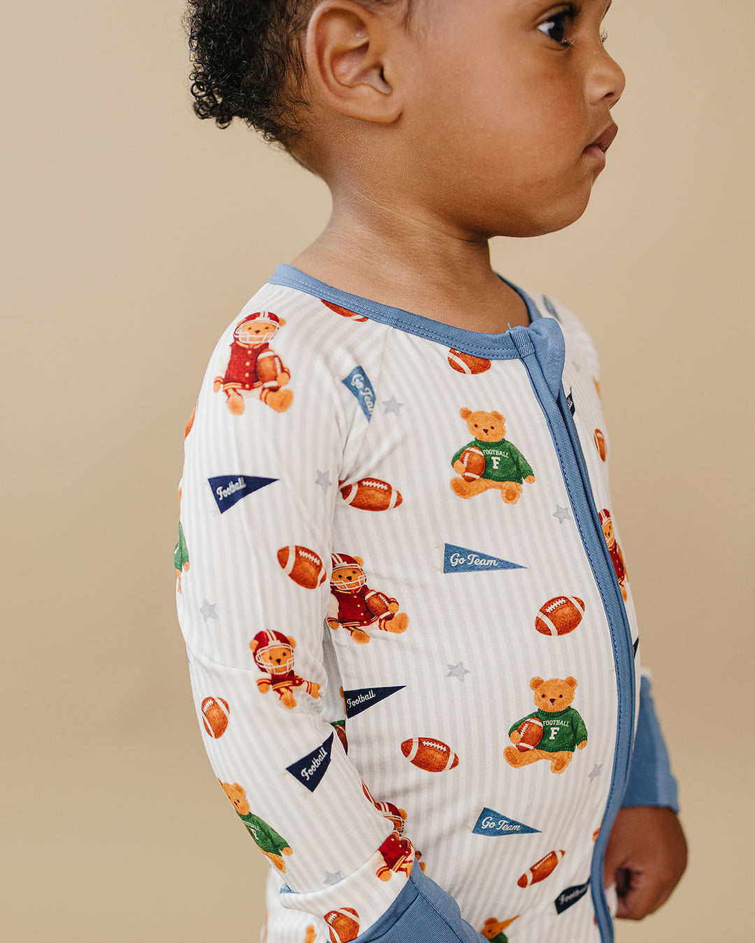 Side close-up of a child wearing the Touchdown Teddy football-print bamboo romper.