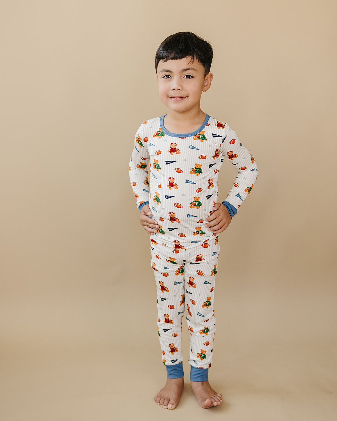 Full-length front view of a child modeling the Touchdown Teddy bamboo pajama set.
