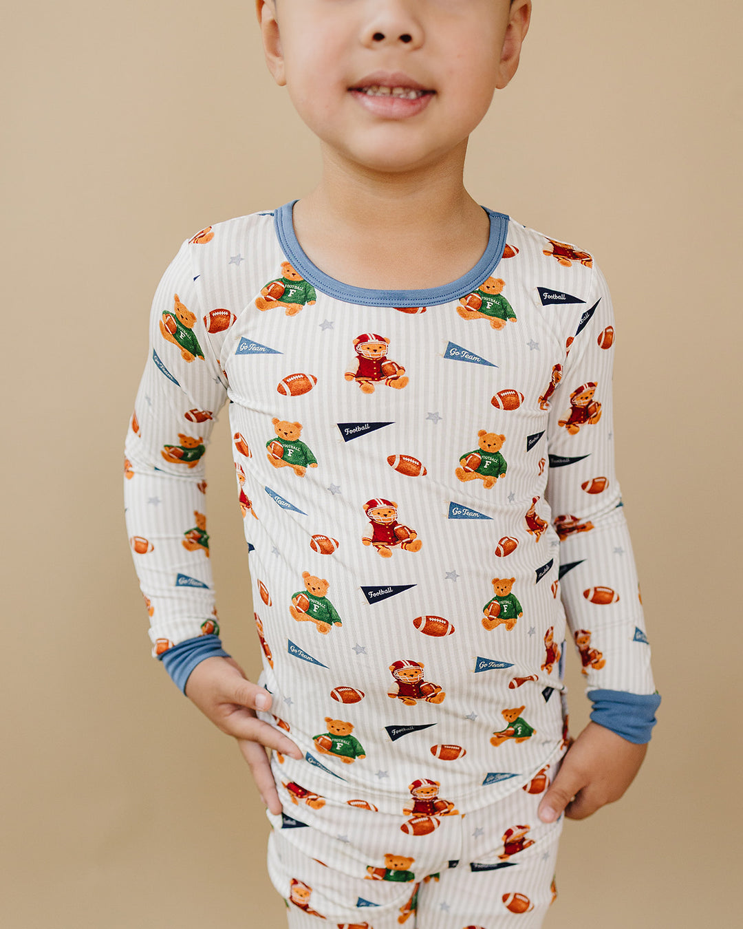 Close-up of a child wearing the Touchdown Teddy bamboo top with dusty blue trim.