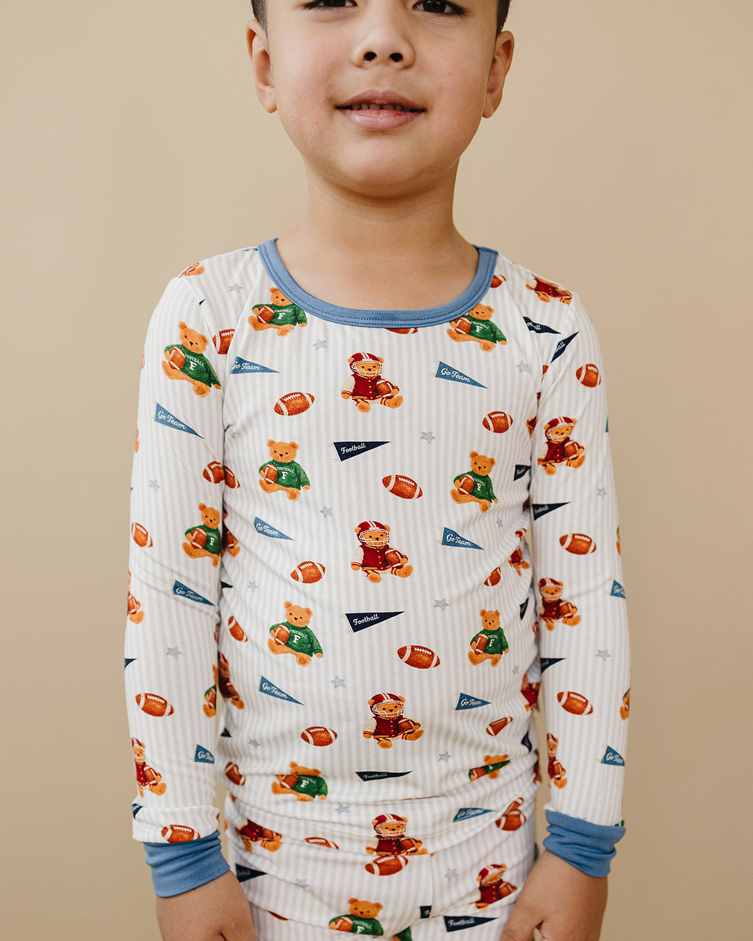 Close-up of a toddler wearing the Touchdown Teddy football-print bamboo two-piece set.