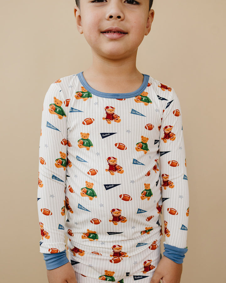 Close-up of a toddler wearing the Touchdown Teddy football-print bamboo two-piece set.