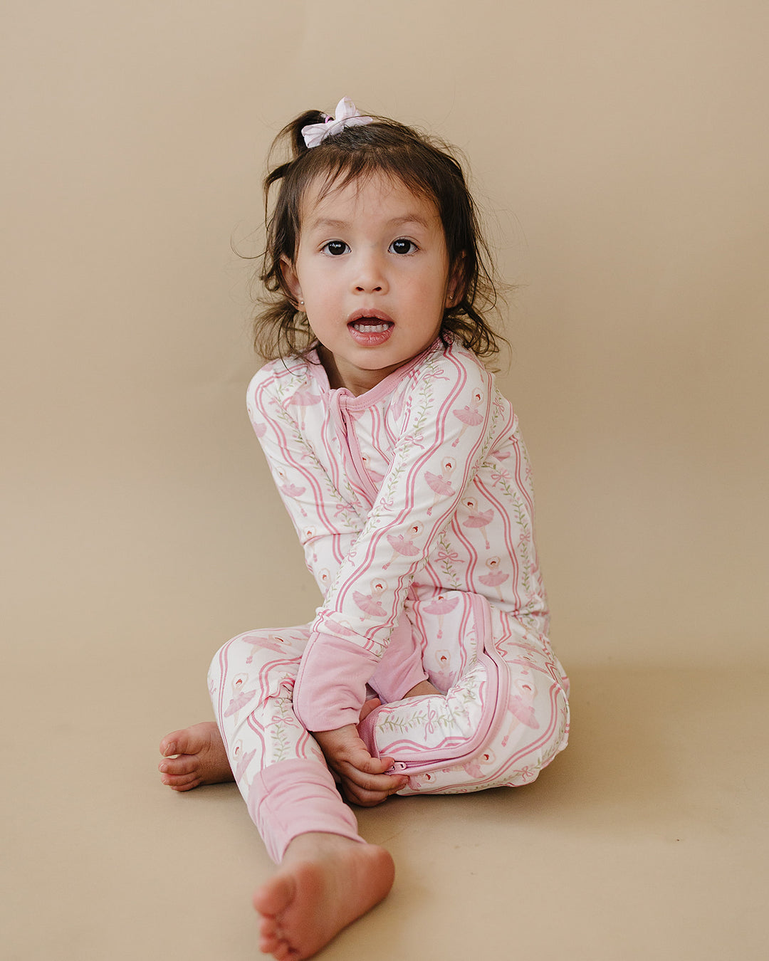 Toddler sitting in the Little Ballerina bamboo zip romper against a neutral background.