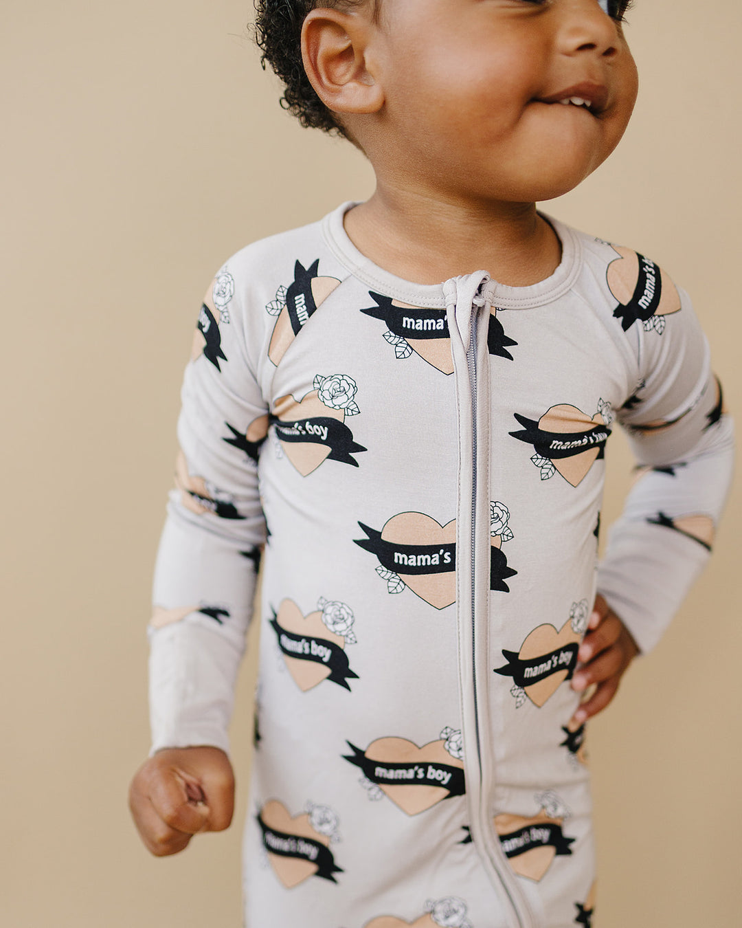 Close-up of a toddler wearing the Mama’s Boy bamboo romper with one hand on their hip.