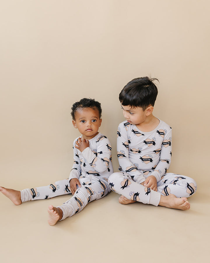 Two children looking at each other while seated in coordinating Mama’s Boy bamboo outfits.