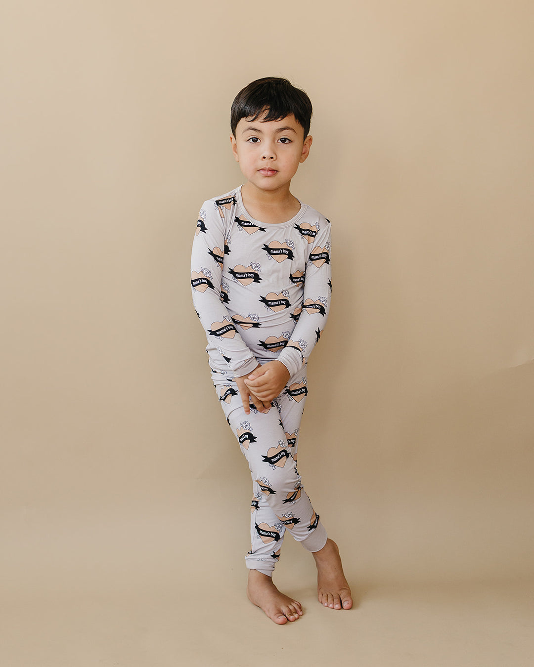 Child standing with ankles crossed in the Mama’s Boy bamboo long-sleeve top and matching pants.
