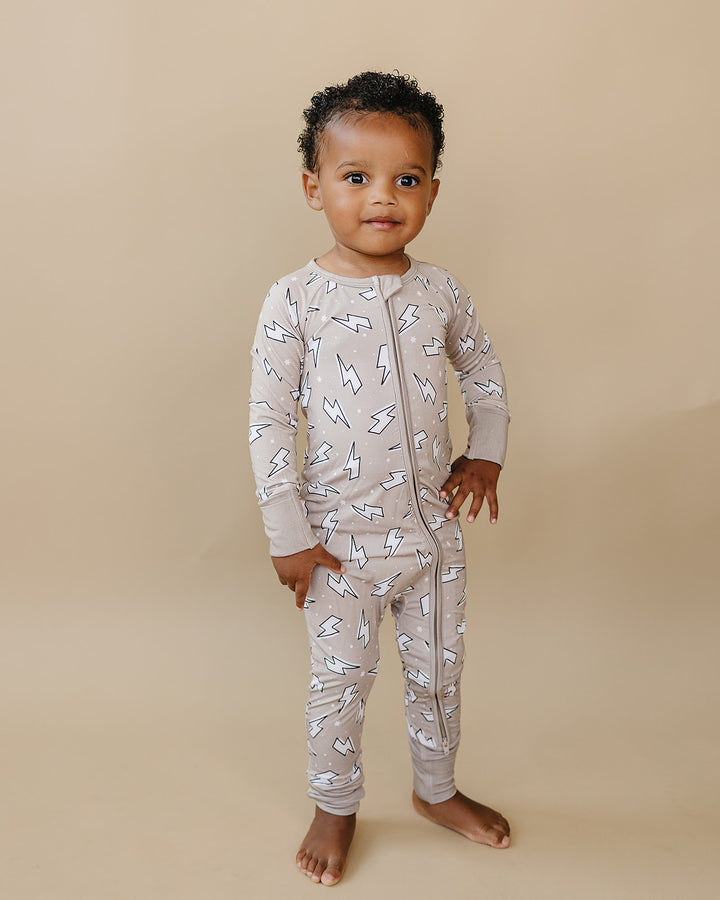 Toddler boy modeling the Latte Bolts bamboo zip romper in a full-length front view.