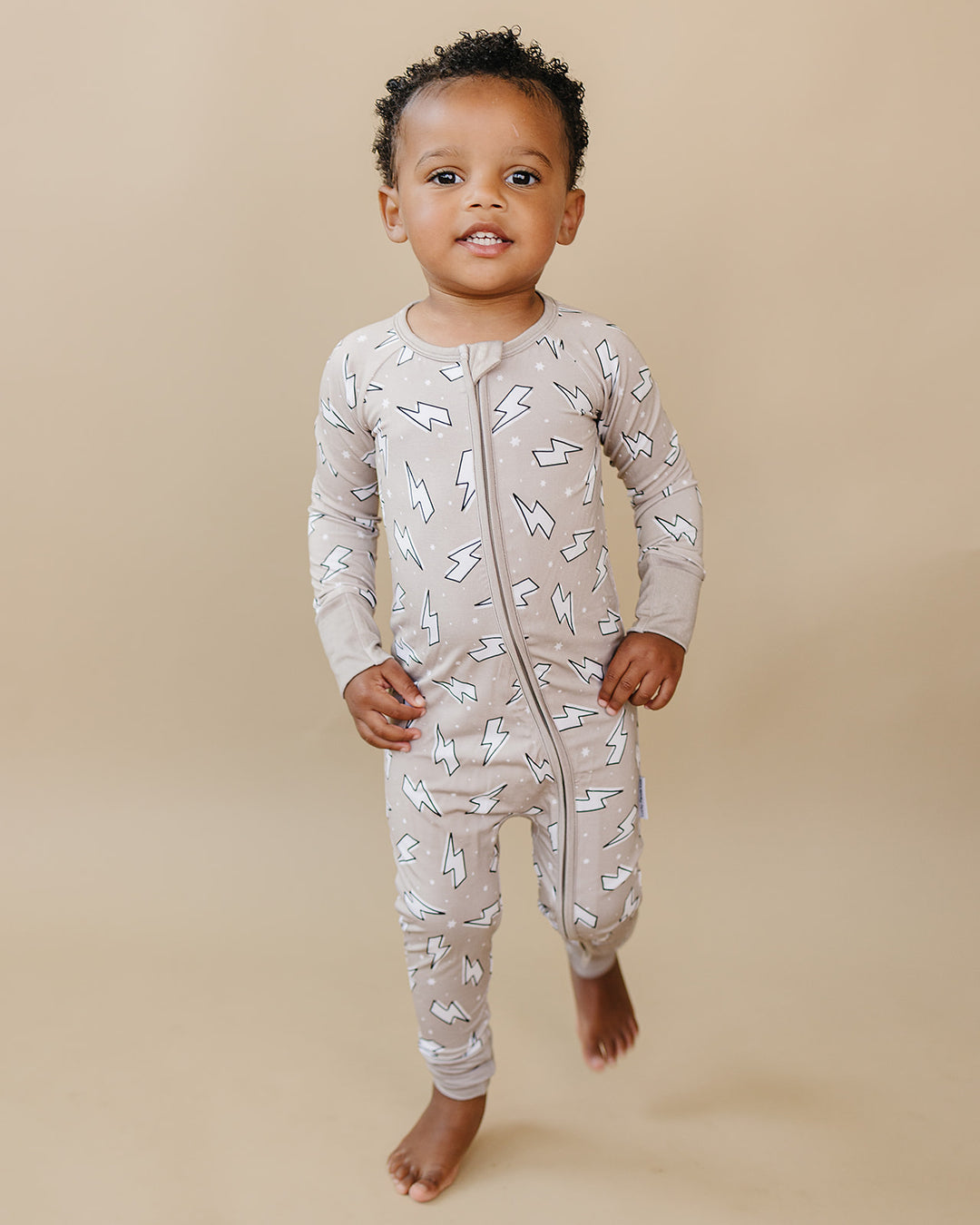 Toddler boy walking forward in the Latte Bolts bamboo zip romper, showing its comfortable fit for movement.
