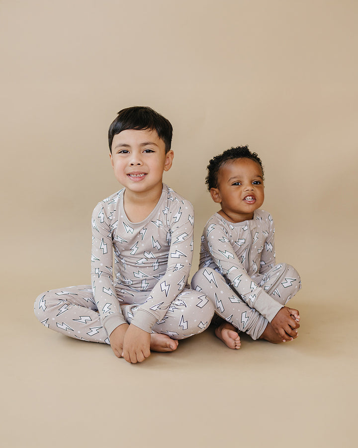 Side view of a toddler boy wearing the Latte Bolts bamboo zip romper with one leg lifted playfully.
