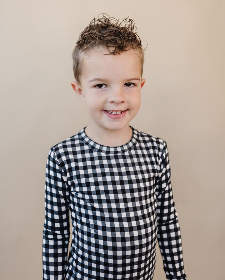 Child wearing the Black Gingham Bamboo Two Piece Set with classic black and white check print