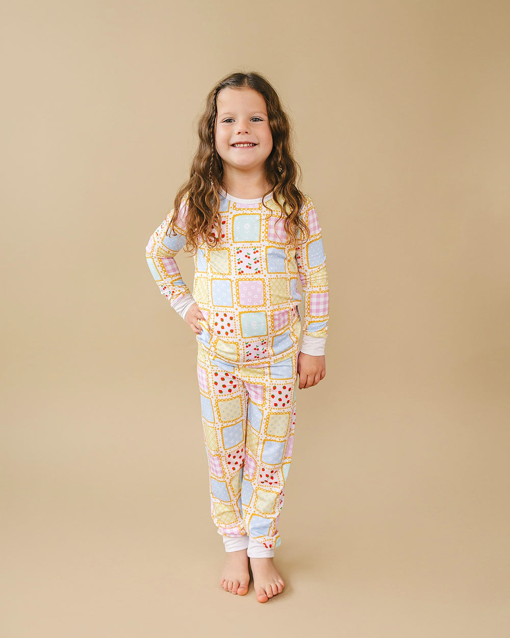 Full length front view of a child in the Sweet Patchwork pajama top and matching pants with white ankle cuffs.
