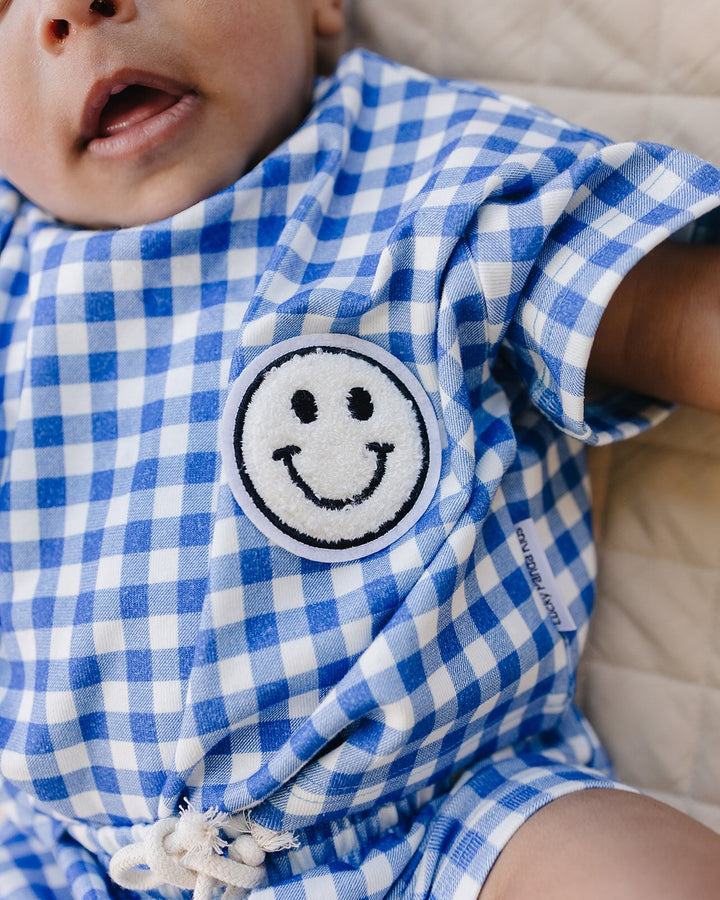 Baby wearing Lucky Panda Kids Blue Gingham Shorts Set — gender neutral cotton two-piece with smiley face patch
Lucky Panda Kids Shorts Set Blue Gingham flat lay — relaxed top with smiley patch and matching elastic waistband shorts
Toddler in Lucky Panda Kids Blue Gingham Shorts Set — sizes 0–3M to 8–9Y, gender neutral summer outfit
Close-up of Lucky Panda Kids Blue Gingham Shorts Set smiley face patch — soft 95% cotton kids two-piece
Lucky Panda Kids Blue Gingham Shorts Set on babies — gender neutral cotton