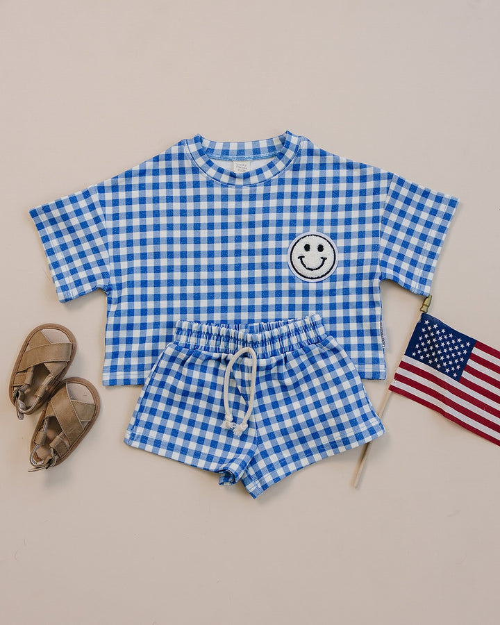 Baby wearing Lucky Panda Kids Blue Gingham Shorts Set — gender neutral cotton two-piece with smiley face patch
Lucky Panda Kids Shorts Set Blue Gingham flat lay — relaxed top with smiley patch and matching elastic waistband shorts
Toddler in Lucky Panda Kids Blue Gingham Shorts Set — sizes 0–3M to 8–9Y, gender neutral summer outfit
Close-up of Lucky Panda Kids Blue Gingham Shorts Set smiley face patch — soft 95% cotton kids two-piece
Lucky Panda Kids Blue Gingham Shorts Set on babies — gender neutral cotton