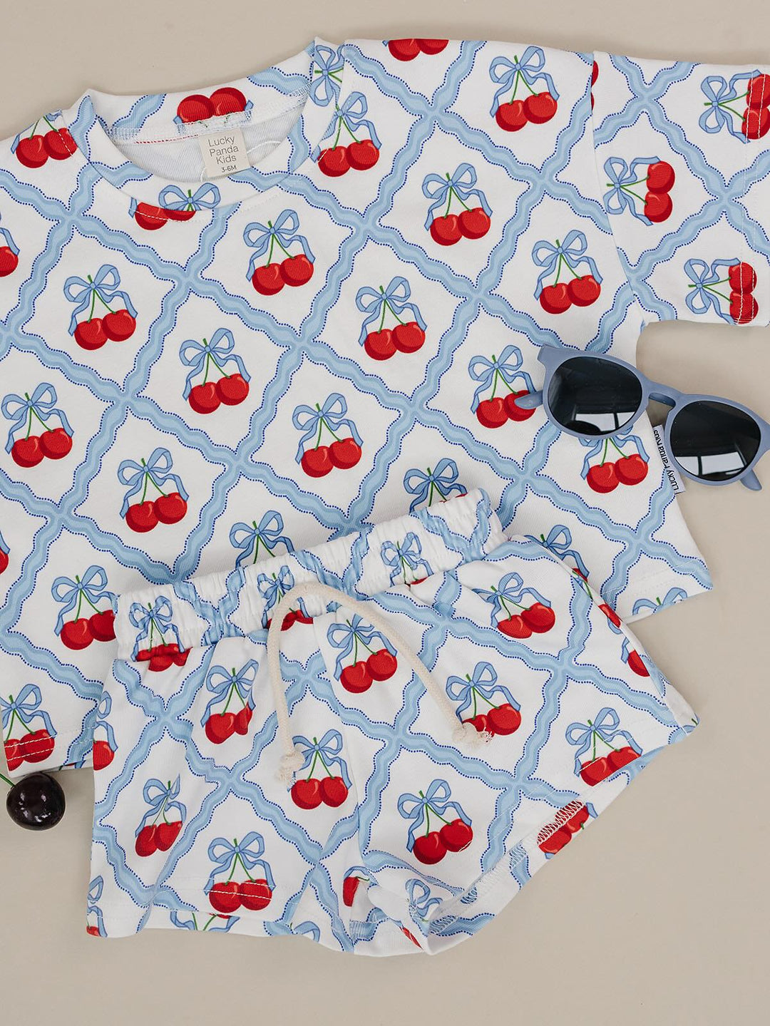 Lucky Panda Kids Sweet Cherry Cotton Shorts Set flat lay — top and shorts.Close-up of Sweet Cherry Cotton Shorts Set fabric showing cherry print and soft cotton texture