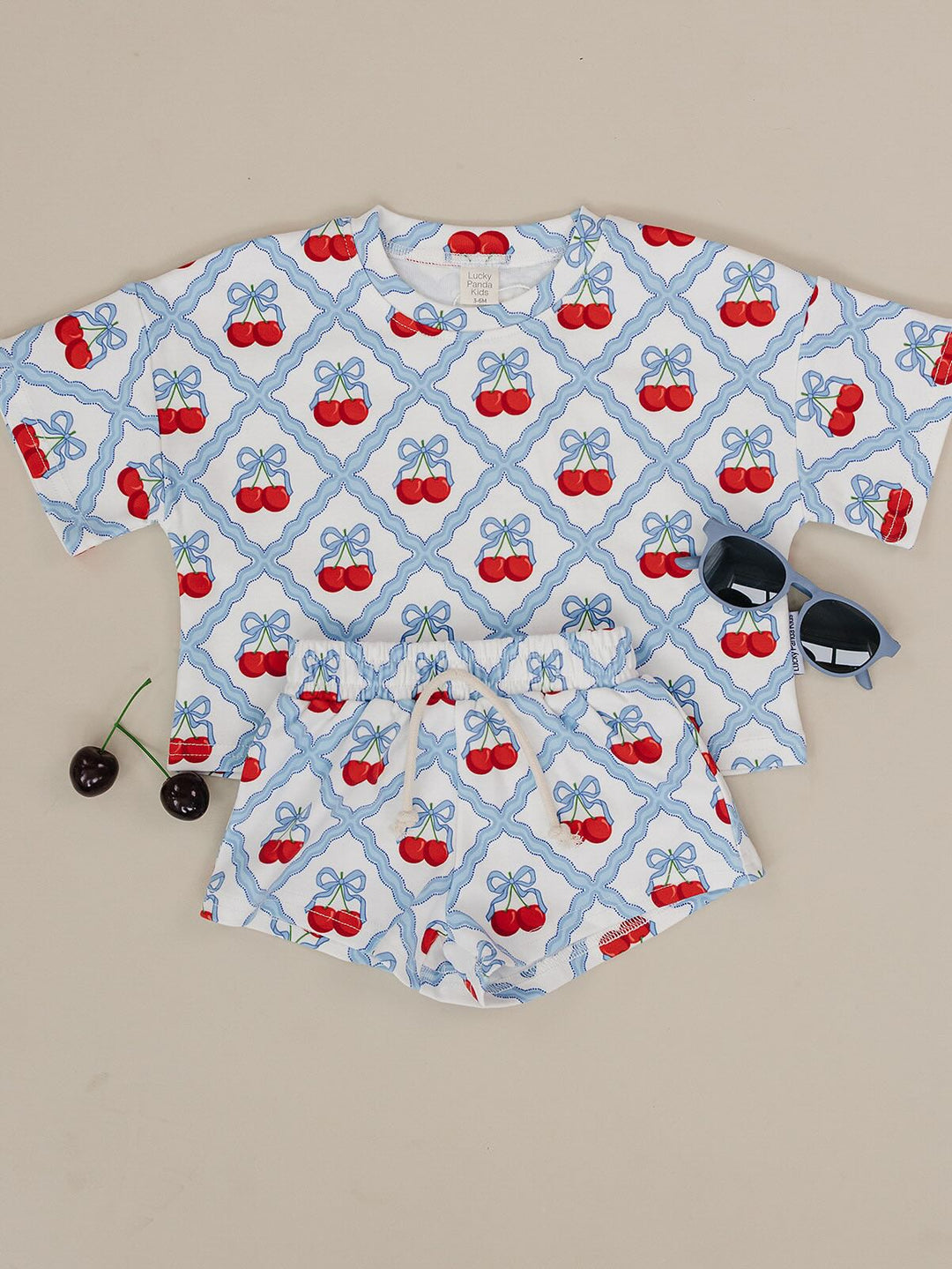 Lucky Panda Kids Sweet Cherry Cotton Shorts Set flat lay — top and shorts.Close-up of Sweet Cherry Cotton Shorts Set fabric showing cherry print and soft cotton texture