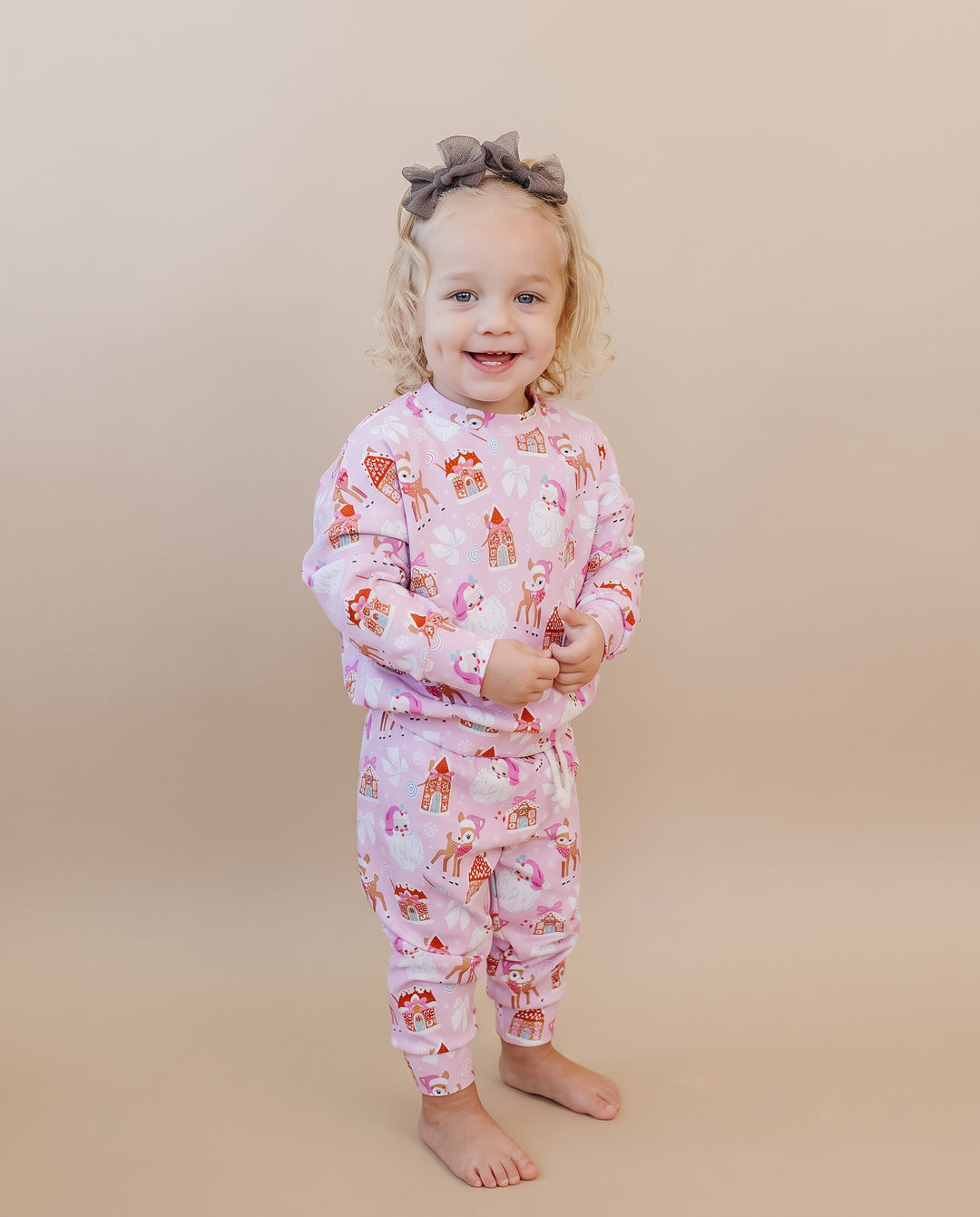 Smiling toddler standing barefoot in the Pink Christmas two piece jogger outfit.