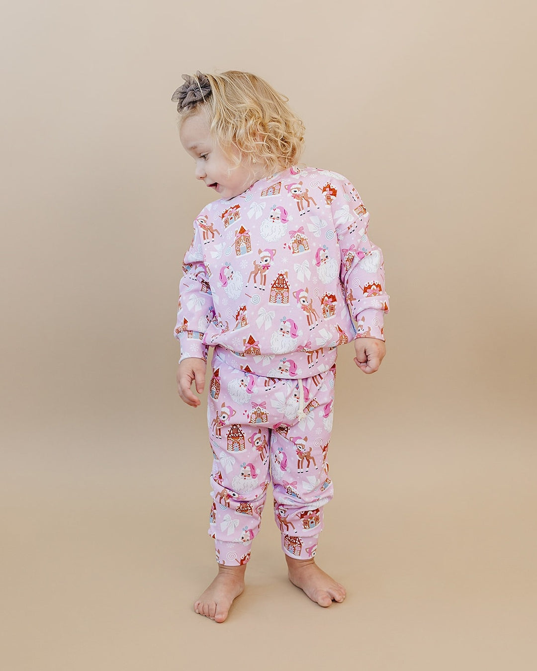 Toddler looking over one shoulder in the Pink Christmas jogger set, showing the back of the top and pants.