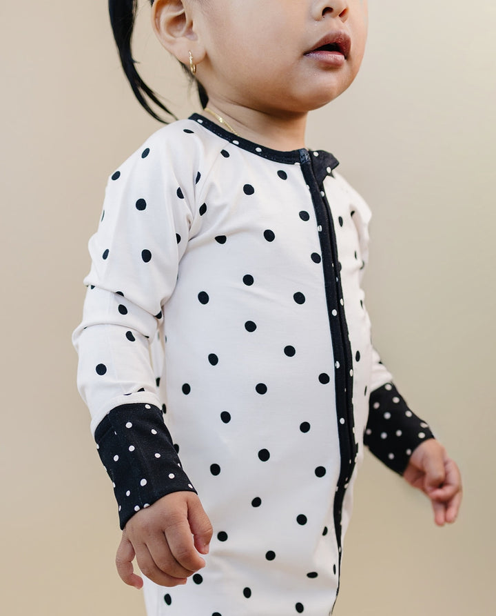 Little one wearing the Classic Polka Bamboo Zip Romper with black trim
