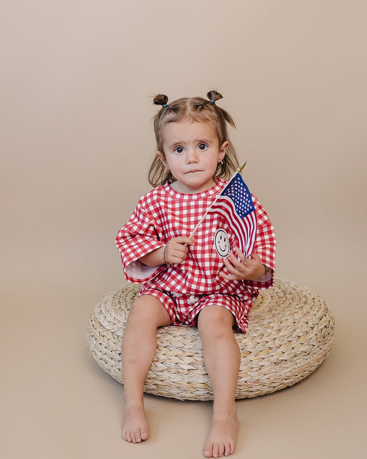 Baby wearing Lucky Panda Kids Red Gingham Shorts Set — gender neutral cotton two-piece with smiley face patch
Lucky Panda Kids Shorts Set Red Gingham flat lay — relaxed top with smiley patch and matching elastic waistband shorts
Toddler in Lucky Panda Kids Red Gingham Shorts Set — sizes 0–3M to 8–9Y, gender neutral summer outfit
Close-up of Lucky Panda Kids Red Gingham Shorts Set smiley face patch — soft 95% cotton kids two-piece
Lucky Panda Kids Red Gingham Shorts Set on baby — gender neutral cotton summer