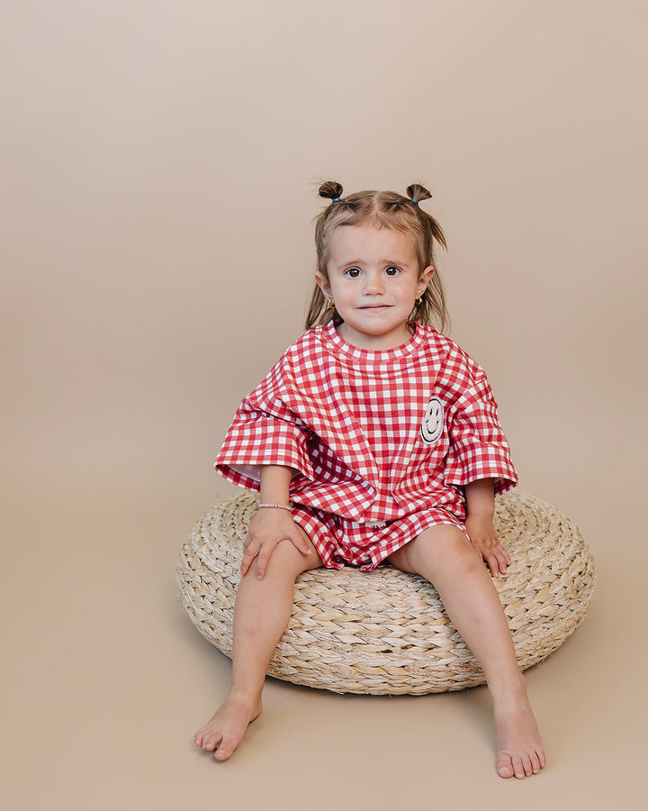 Baby wearing Lucky Panda Kids Red Gingham Shorts Set — gender neutral cotton two-piece with smiley face patch
Lucky Panda Kids Shorts Set Red Gingham flat lay — relaxed top with smiley patch and matching elastic waistband shorts
Toddler in Lucky Panda Kids Red Gingham Shorts Set — sizes 0–3M to 8–9Y, gender neutral summer outfit
Close-up of Lucky Panda Kids Red Gingham Shorts Set smiley face patch — soft 95% cotton kids two-piece
Lucky Panda Kids Red Gingham Shorts Set on baby — gender neutral cotton summer