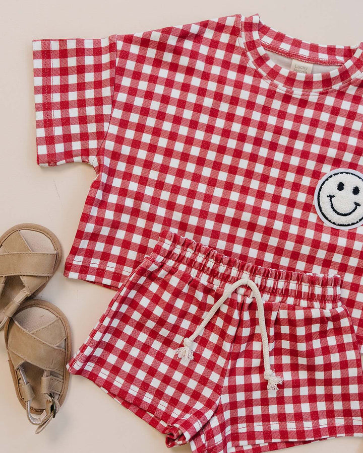 Baby wearing Lucky Panda Kids Red Gingham Shorts Set — gender neutral cotton two-piece with smiley face patch
Lucky Panda Kids Shorts Set Red Gingham flat lay — relaxed top with smiley patch and matching elastic waistband shorts
Toddler in Lucky Panda Kids Red Gingham Shorts Set — sizes 0–3M to 8–9Y, gender neutral summer outfit
Close-up of Lucky Panda Kids Red Gingham Shorts Set smiley face patch — soft 95% cotton kids two-piece
Lucky Panda Kids Red Gingham Shorts Set on baby — gender neutral cotton summer