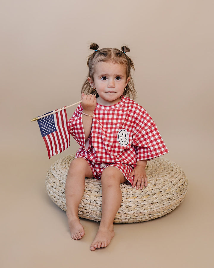 Baby wearing Lucky Panda Kids Red Gingham Shorts Set — gender neutral cotton two-piece with smiley face patch
Lucky Panda Kids Shorts Set Red Gingham flat lay — relaxed top with smiley patch and matching elastic waistband shorts
Toddler in Lucky Panda Kids Red Gingham Shorts Set — sizes 0–3M to 8–9Y, gender neutral summer outfit
Close-up of Lucky Panda Kids Red Gingham Shorts Set smiley face patch — soft 95% cotton kids two-piece
Lucky Panda Kids Red Gingham Shorts Set on baby — gender neutral cotton summer