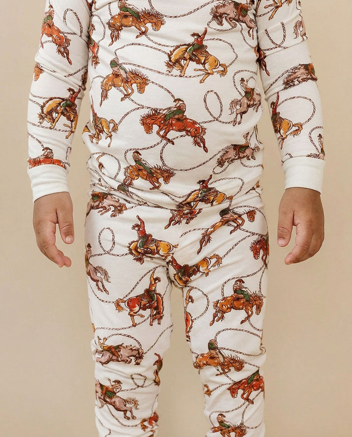 Children's pajamas with cowboy and horse pattern on a beige background