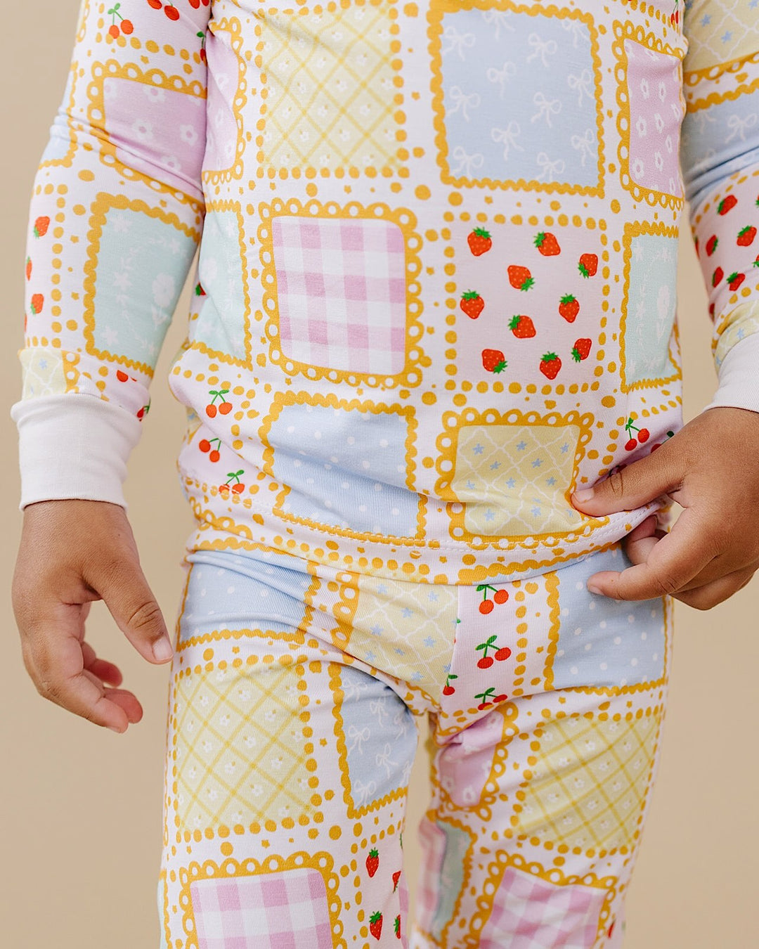Detail of Sweet Patchwork pajamas showing the top hem, matching pants and pastel strawberry and gingham squares.