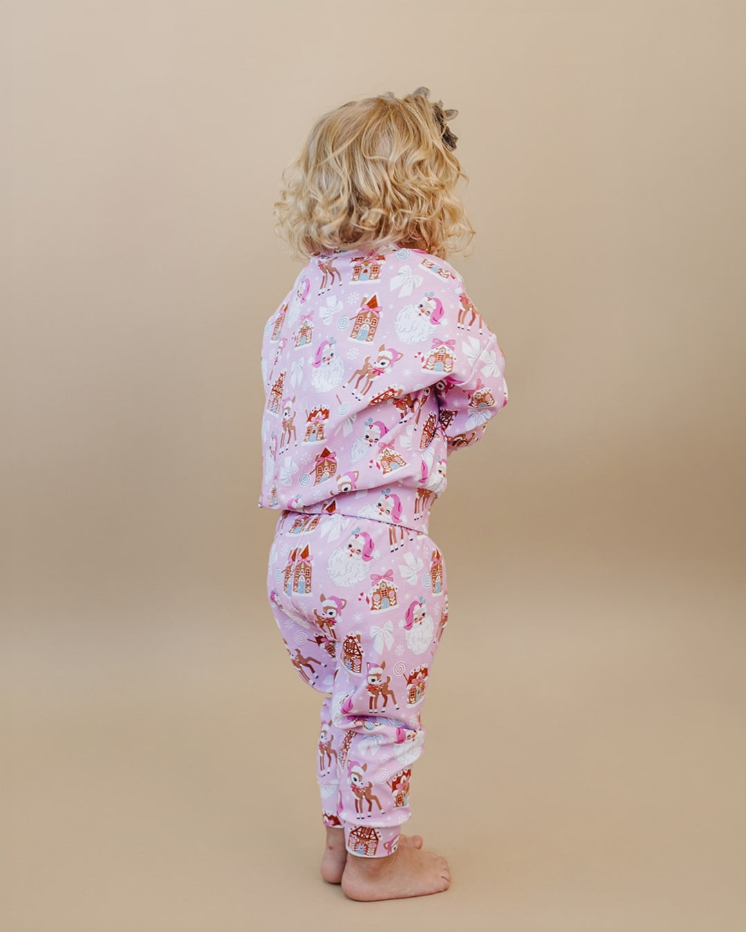 Back view of a toddler wearing the Pink Christmas long sleeve top and matching jogger pants.