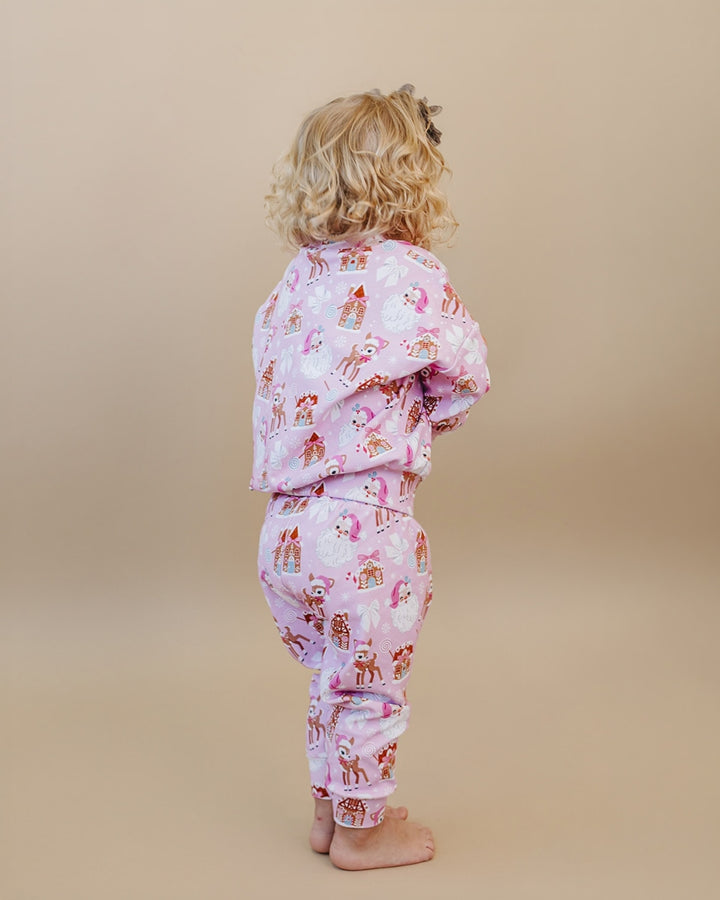 Back view of a toddler wearing the Pink Christmas long sleeve top and matching jogger pants.
